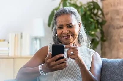 Senior woman smiling while using her smartphone
